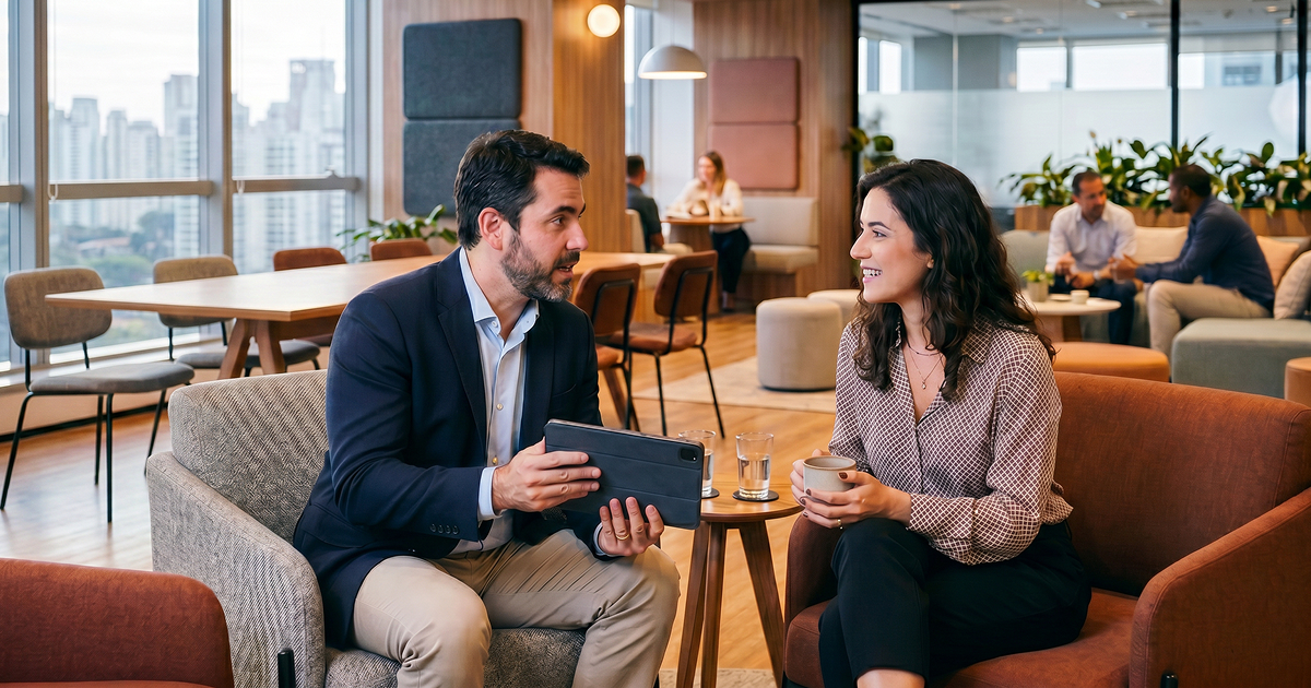 Dois profissionais conversando em uma área de convivência de um escritório de fintech em São Paulo.